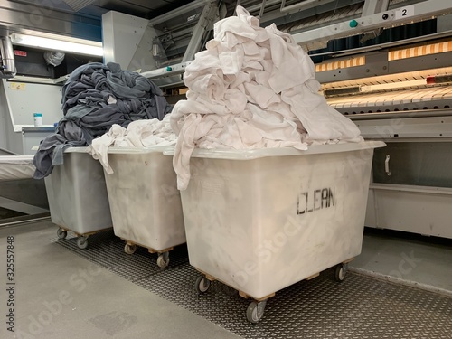 Laundry crew are working on the cruise ship. Huge operation on a luxury vessel. White trolley. Staff is wearing a professional uniform.