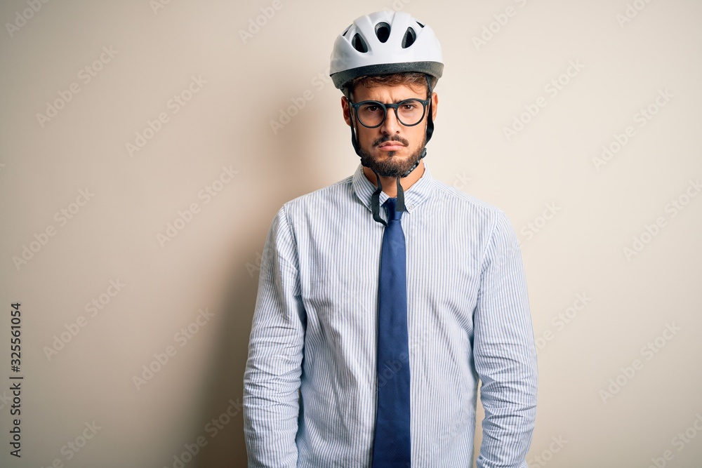 Young businessman wearing glasses and bike helmet standing over isolated white bakground skeptic and nervous, frowning upset because of problem. Negative person.