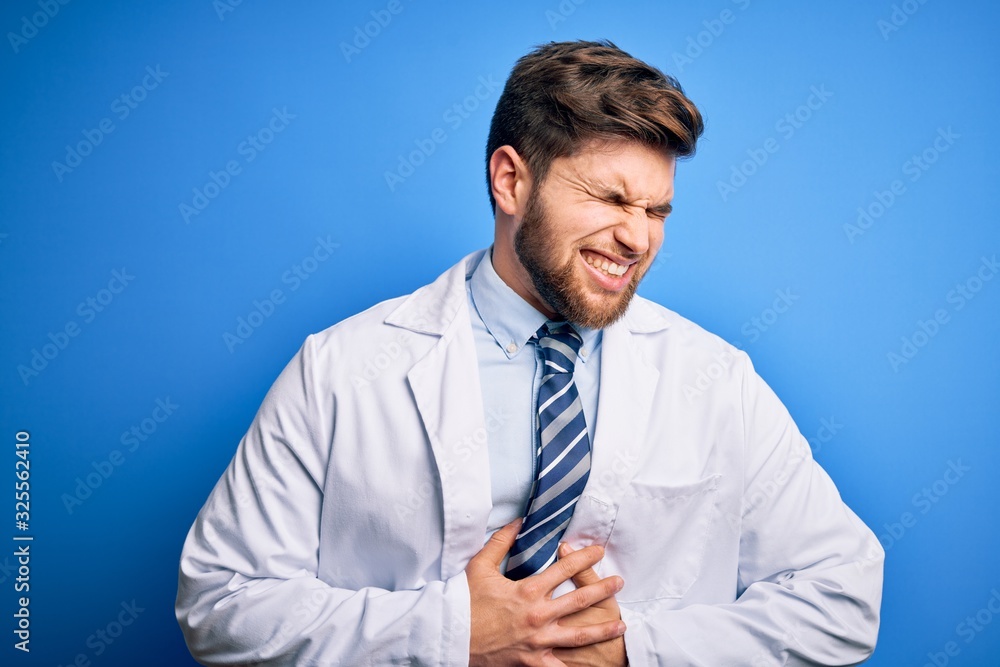 Young blond therapist man with beard and blue eyes wearing coat and tie over background with hand on stomach because nausea, painful disease feeling unwell. Ache concept. Young blond therapist man with beard and blue eyes wearing coat and tie over background with hand on stomach because nausea, painful disease feeling unwell. Ache concept.