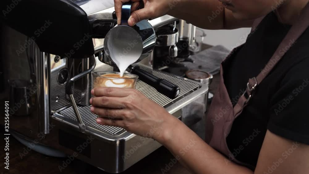 Barista making Latte art with milk foam in tumbler glass Barista making Latte art with milk foam in tumbler glass