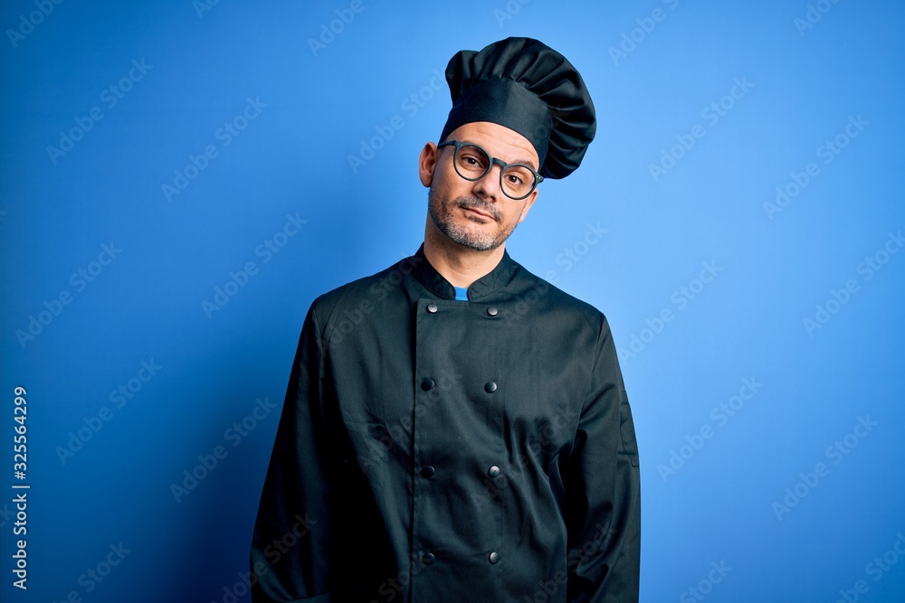 Young handsome chef man wearing cooker uniform and hat over isolated blue background looking sleepy and tired, exhausted for fatigue and hangover, lazy eyes in the morning. Young handsome chef man wearing cooker uniform and hat over isolated blue background looking sleepy and tired, exhausted for fatigue and hangover, lazy eyes in the morning.