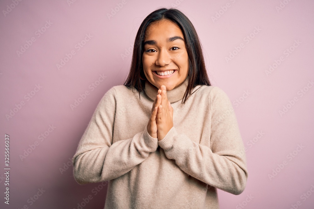 Young beautiful asian woman wearing casual turtleneck sweater over pink background praying with hands together asking for forgiveness smiling confident. Young beautiful asian woman wearing casual turtleneck sweater over pink background praying with hands together asking for forgiveness smiling confident.