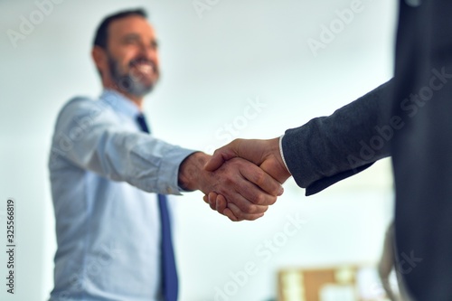 Businessmen standing together shaking hands for agreement at the office
