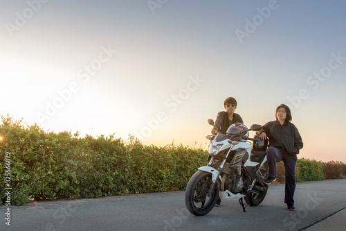 Asian man and woman with helmet and wearing and fasten before riding big bike motorcycle on the road for safety