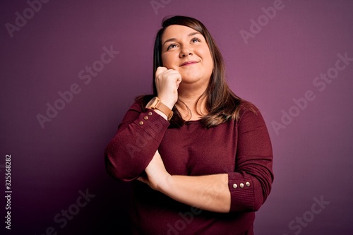 Beautiful brunette plus size woman wearing casual sweater over isolated purple background with hand on chin thinking about question, pensive expression. Smiling with thoughtful face. Doubt concept. © Krakenimages.com