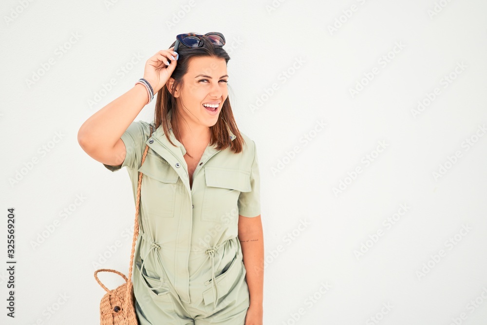 Beautiful girl leaning on white wall, young friendly woman smiling happy on a sunny day of summer Beautiful girl leaning on white wall, young friendly woman smiling happy on a sunny day of summer