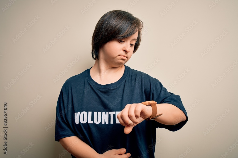 Young down syndrome volunteer woman wearing social care charity t-shirt Checking the time on wrist watch, relaxed and confident Young down syndrome volunteer woman wearing social care charity t-shirt Checking the time on wrist watch, relaxed and confident