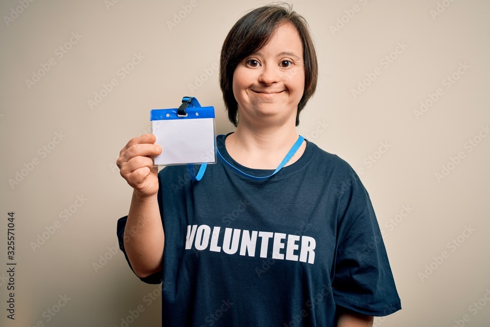 Young down syndrome volunteer woman wearing social care charity t-shirt showing identification with a happy face standing and smiling with a confident smile showing teeth Young down syndrome volunteer woman wearing social care charity t-shirt showing identification with a happy face standing and smiling with a confident smile showing teeth