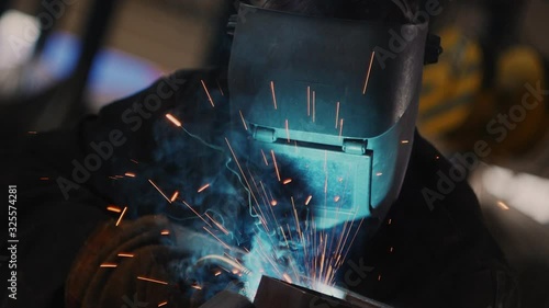 welder in special mask connects metal parts at bright sparks photo
