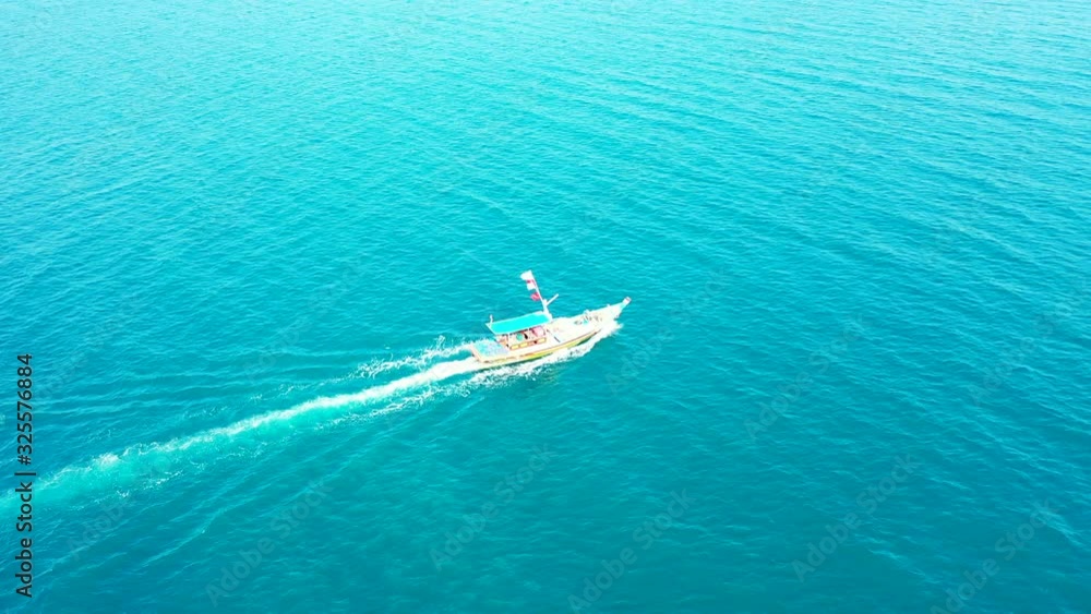 Touring boat sailing slowly across azure sea surface with vibrant water reflecting bright blue sky over tropical islands Touring boat sailing slowly across azure sea surface with vibrant water reflecting bright blue sky over tropical islands