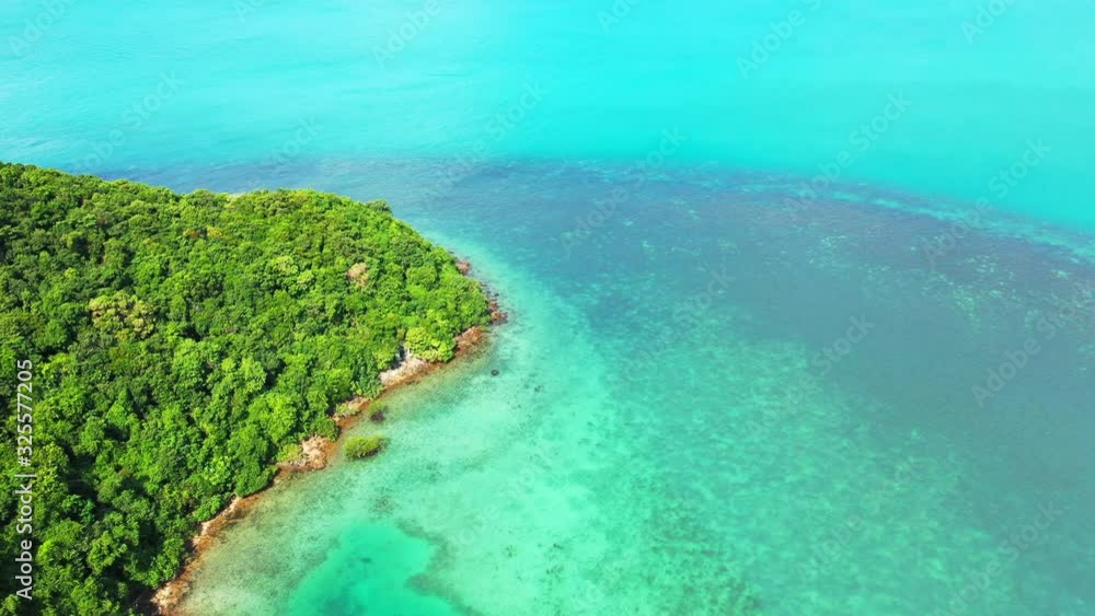 Beautiful coral reefs barrier under turquoise lagoon surrounding rocky coastline of tropical island cape with green vegetation, Thailand Beautiful coral reefs barrier under turquoise lagoon surrounding rocky coastline of tropical island cape with green vegetation, Thailand