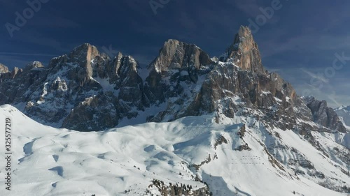 Majestic view of Passo Rolle - a high mountain pass in Trentino in Italy. It connects the Fiemme and Primiero valleys. A spiky crown of mountain peaks towering over the snow-covered plateau. photo