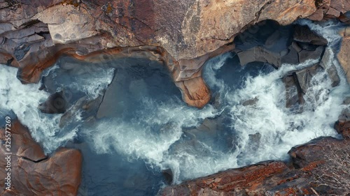 The turbid waters of the Storelva river rushing on rapidly below,  splashing and eddying against the beautifully carved walls of the channel. photo