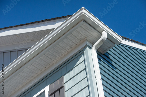 Colonial white gutter guard system, fascia, drip edge, soffit providing ventilation to the attic, with pacific blue vinyl horizontal siding at a luxury American single family home neighborhood USA photo