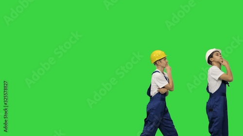 Three construction workers walking in a funny dacning way looking at objects around them on a Green Screen, Chroma Key. photo