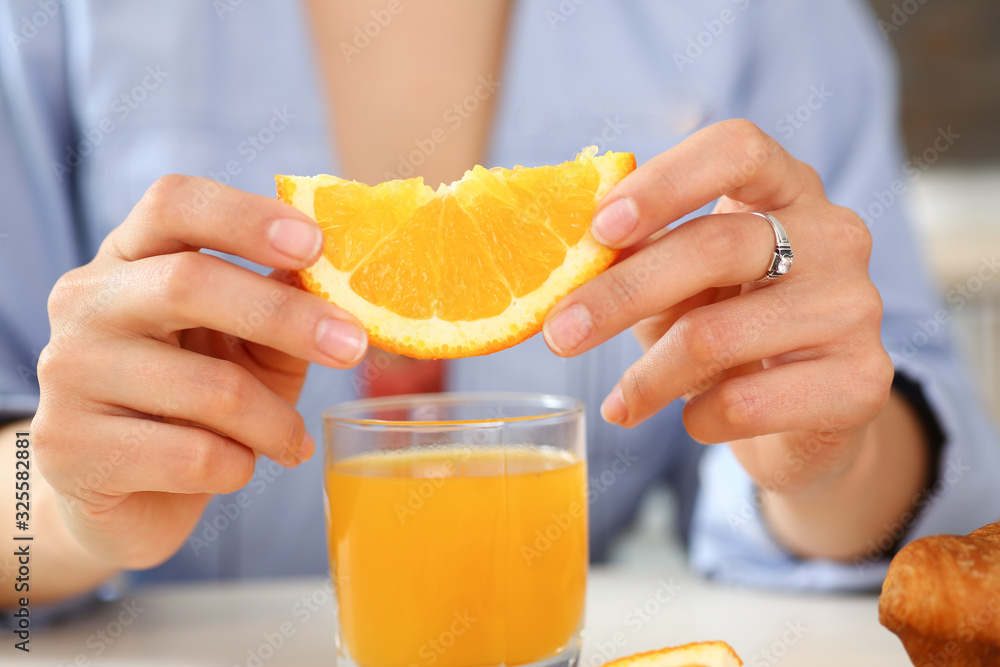 A woman holds a slice of sliced orange in her hand during an early breakfast in the kitchen the concept of a healthy diet A woman holds a slice of sliced orange in her hand during an early breakfast in the kitchen the concept of a healthy diet
