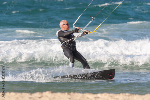 A man over 60 years old rides a kiteboarding