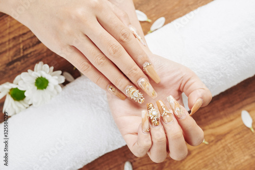 Woman showing her fancy creative manicure with golden polish and jewelry rhinestones