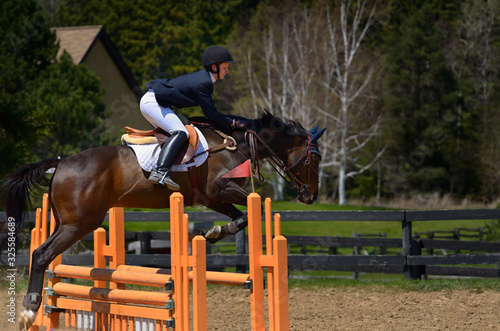 Horse rider jumping over an oxer fence at an outdoor equestrian show competition