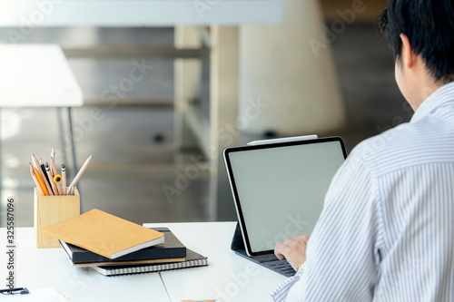 Young man working with tablet while sitting in modern office.