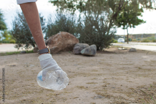 Hand in white gloves taking a plastic bottle from the floor
