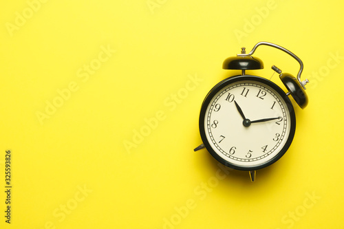 twin bell alarm clock on yellow background. copy space. flat lay