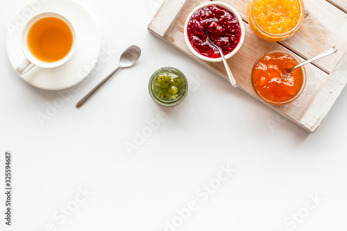 Fruit jam near tea on white kitchen desk frame copy space photo