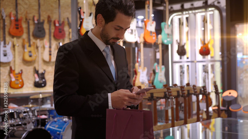 Wallpaper Mural An upwardly mobile Middle Eastern man using a mobile phone - smartwatch to purchase product at the point of sale terminal in a retail store with nfc identification payment for verification Torontodigital.ca