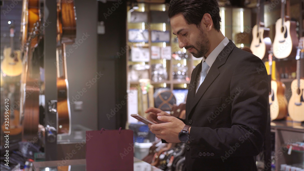 An upwardly mobile Middle Eastern man using a mobile phone - smartwatch to purchase product at the point of sale terminal in a retail store with nfc identification payment for verification