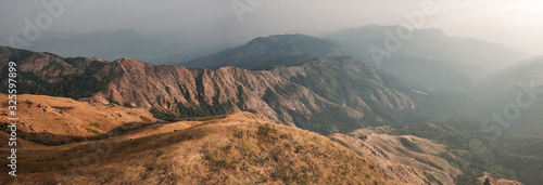 Panorama scenic mountain peaks and ridges stretching during the evening. , Golden grass moving on wind. At Mulayit Taung in Myanmar. is soft focus. © Wuttichai