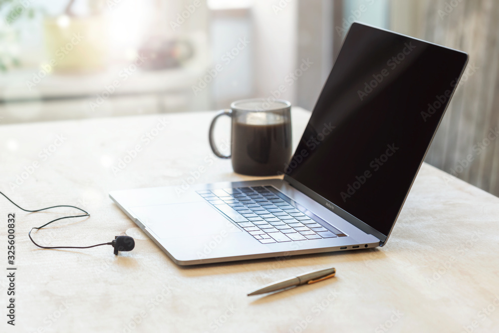 Home education or work outside office concept. Laptop with a microphone and cup of coffee on the table Home education or work outside office concept. Laptop with a microphone and cup of coffee on the table