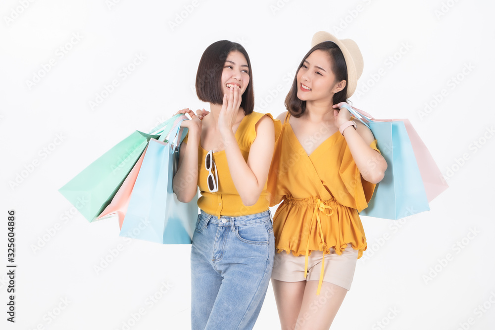 Asian pretty young woman sitting on whitel background. She smiling and  happy shopping bags. she nice-looking lovely attractive shine.Friend  happy to shopping time.