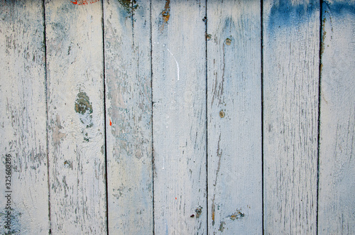 Old peeling pine vertical wooden planks, painted white with traces of nails and knots. Abstract wooden background, texture.