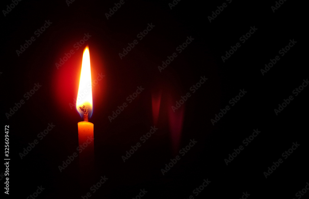 Candle with a flame on a black background with a copy space.Death and loss of a person.Background and composition of various rituals.Memory and grief for the lost person.Space for text.Church candle. Candle with a flame on a black background with a copy space.Death and loss of a person.Background and composition of various rituals.Memory and grief for the lost person.Space for text.Church candle.