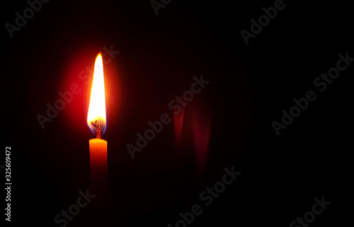 Candle with a flame on a black background with a copy space.Death and loss of a person.Background and composition of various rituals.Memory and grief for the lost person.Space for text.Church candle.