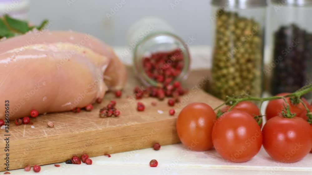 Raw chicken breast with cherry tomatoes and parsleyon wood cuttingboard. Preparation for cooking raw chicken fillet. Raw chicken breast with cherry tomatoes and parsleyon wood cuttingboard. Preparation for cooking raw chicken fillet.