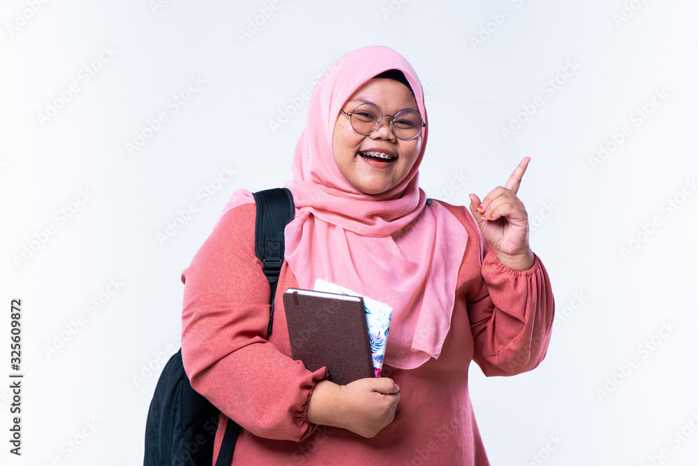 Portrait of a beautiful woman smiling. Young students with their fingers point upwards in a white background Portrait of a beautiful woman smiling. Young students with their fingers point upwards in a white background