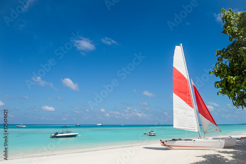 Fototapeta Naklejka Na Ścianę i Meble -  Sailing boat with red and white sail on beach of tropical island, Maldives at sunny day
