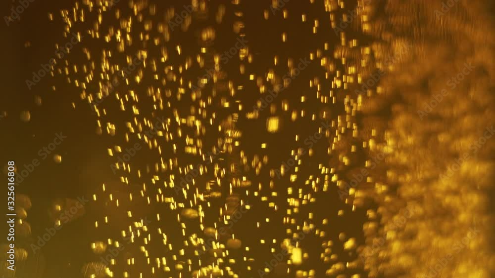 Closeup of sparkling beer. Bubbles rise. Delicious alcoholic drink in golden color. Can also be used as background particle. Closeup of sparkling beer. Bubbles rise. Delicious alcoholic drink in golden color. Can also be used as background particle.