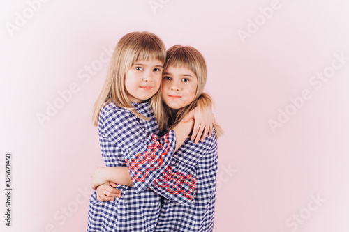 Happy adorable twin blodnie caucasian girls together having fun, hugging and playing. Smilling happy kids. Childhood, twins, friendship concept 