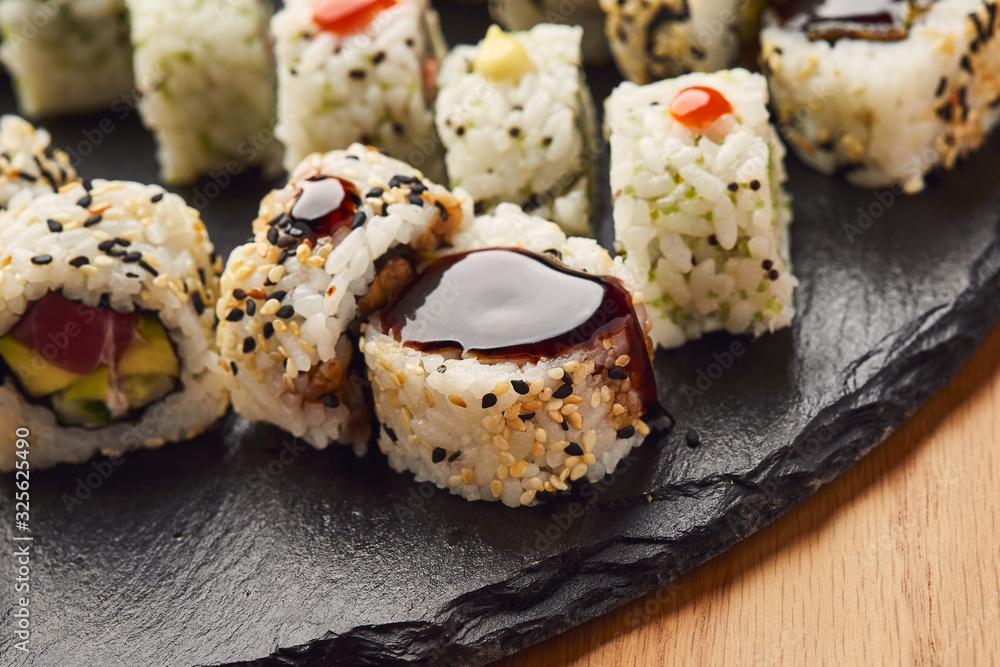 Various kinds of sushi roll set served on black stone. Japanese food
