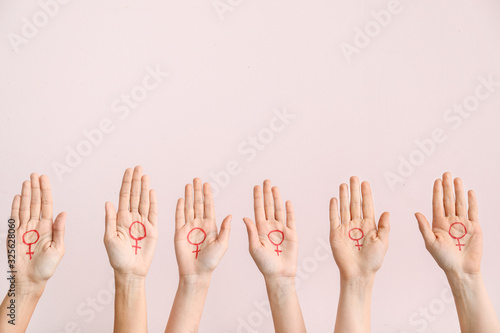 Fotografía Women with drawn symbols of woman on their palms against color background