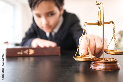 Little lawyer with scales of justice and book in office photo