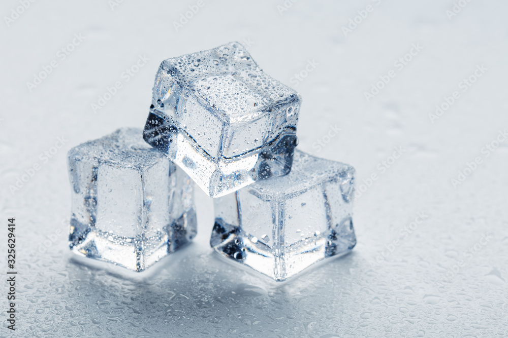 Ice cubes in the form of a pyramid with water drops close - up in macro on a white background. Ice cubes in the form of a pyramid with water drops close - up in macro on a white background.