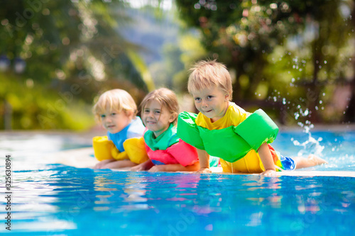Kids in swimming pool. Life jacket for child. © famveldman