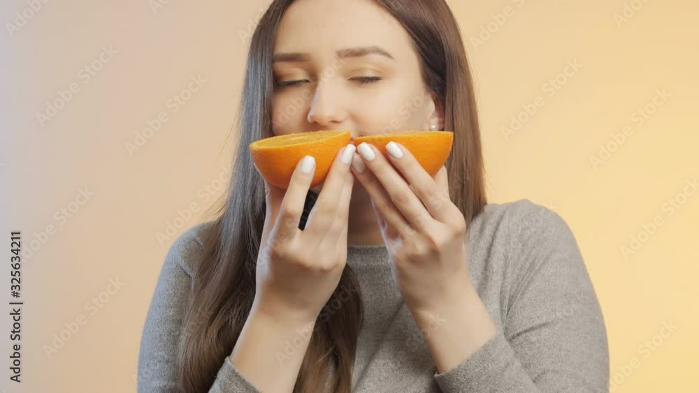 cute girl enjoting smell halfs of orange fruit in hands, girl make cute face grimace, funny emotions, positive mood cute girl enjoting smell halfs of orange fruit in hands, girl make cute face grimace, funny emotions, positive mood