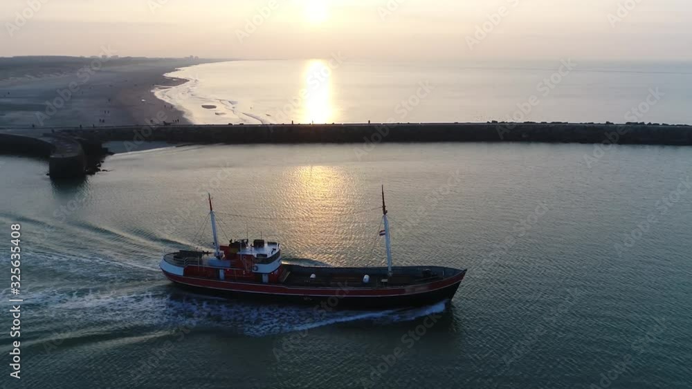 Aerial view of a medium large fishing vessel a boat or ship sailing out during sundown to catch fish in the ocean located in The Netherlands on North Sea coastal part of country 4k high resolution Aerial view of a medium large fishing vessel a boat or ship sailing out during sundown to catch fish in the ocean located in The Netherlands on North Sea coastal part of country 4k high resolution