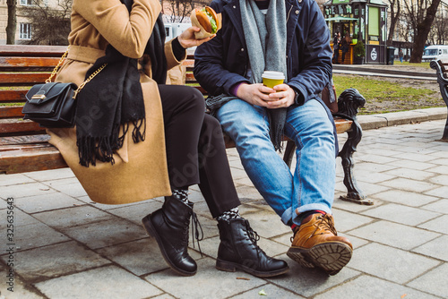 crop image. couple sitting on bench eating fast food drinking tea