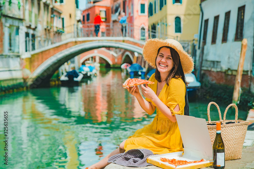 woman sitting on pond with view of venice canal eating pizza