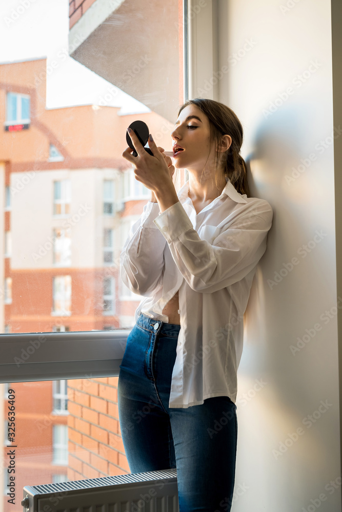 girl doing itself makeup near window in the background before taking a photossesion.